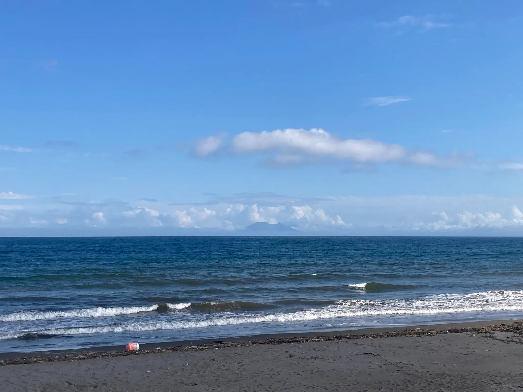 一面の海、遠くに1つのそびえ立った山が見える