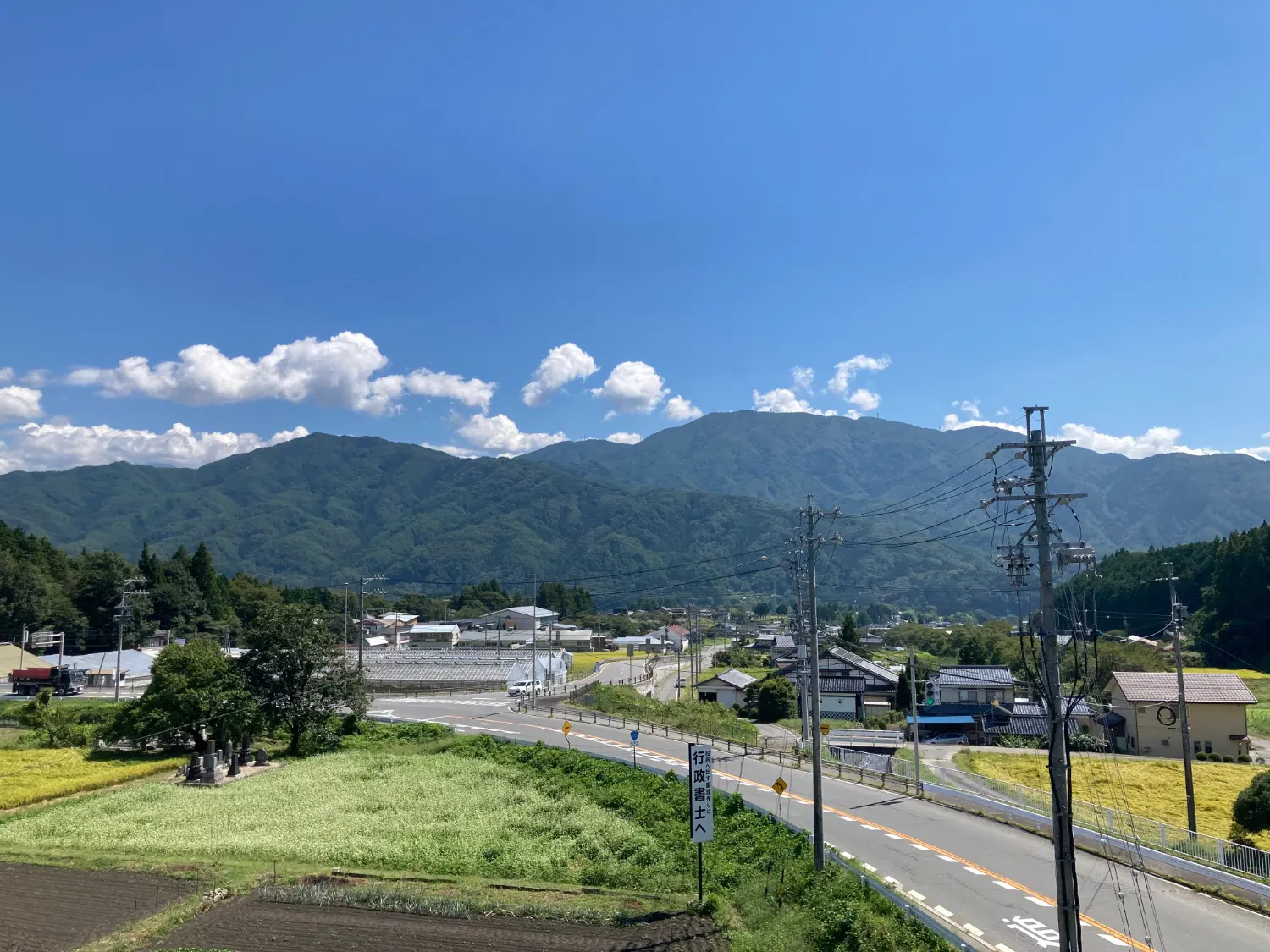 2車線の国道と家と畑が混じった景色