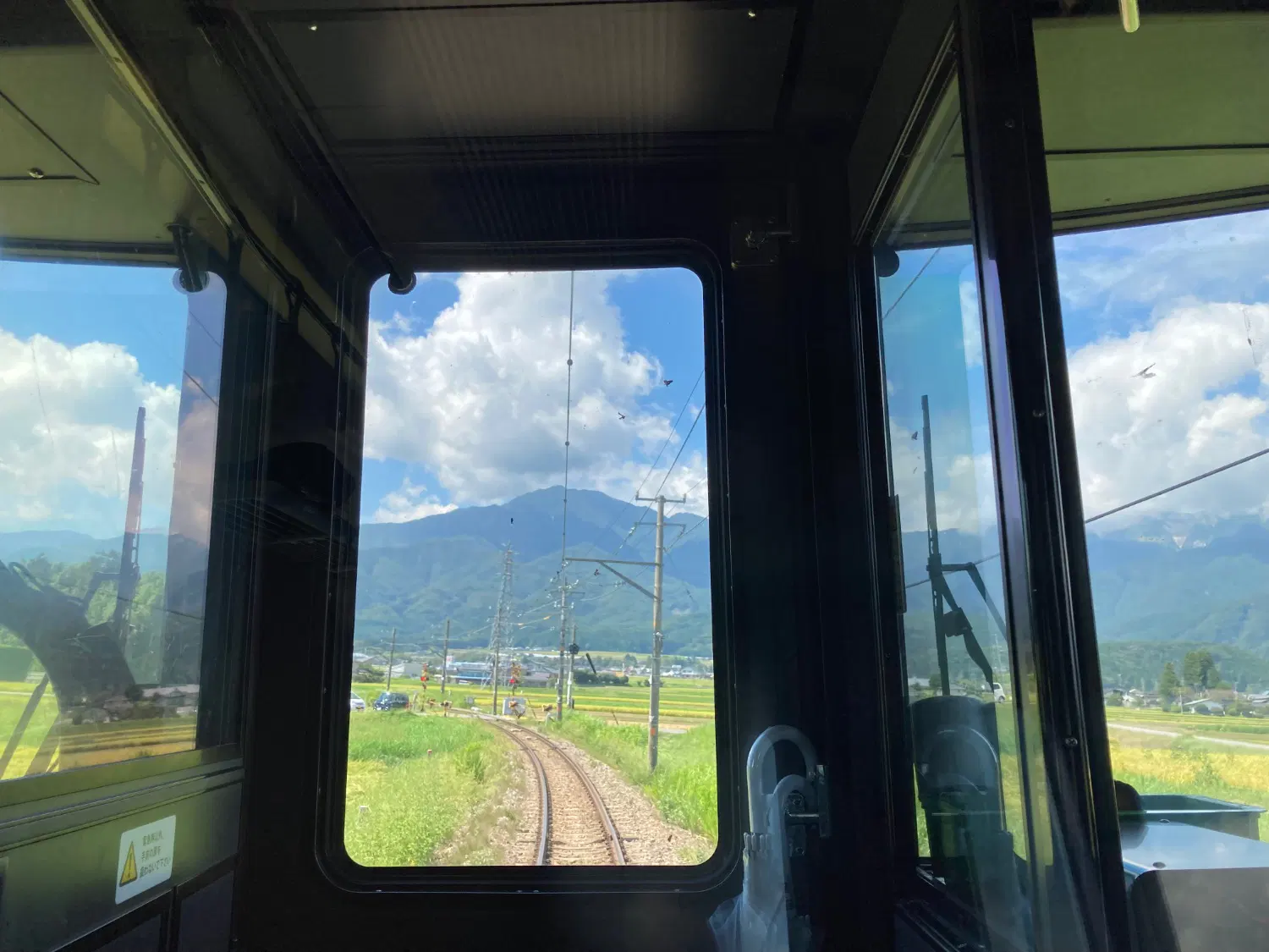 列車の前方がカーブしていて、窓越しに山が見える